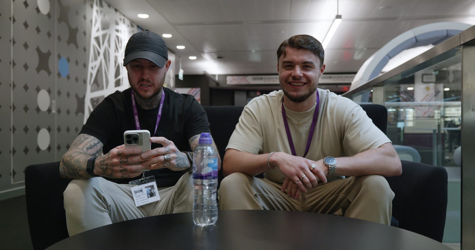 Two smilling men sitting in a chair facing the camera